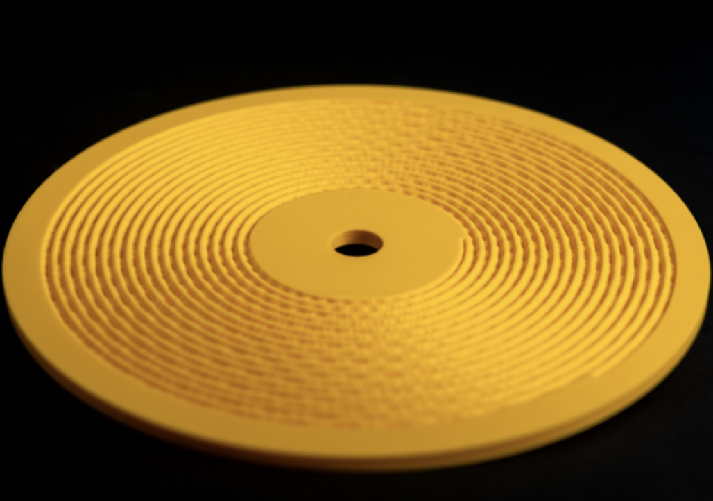 Yellow Kräftsound development print with a visible printed spiral groove